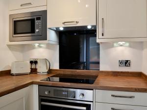a kitchen with a stove and a microwave at Ghillie Cottage in Cockermouth