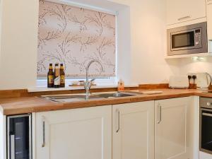 a kitchen with a sink and a microwave at Ghillie Cottage in Cockermouth