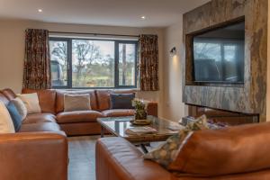 a living room with a leather couch and a tv at Elder howe in Penrith