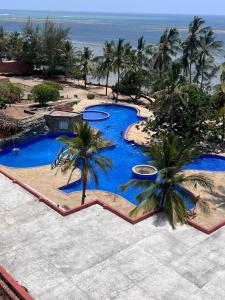 an aerial view of a pool with palm trees and the ocean at Ocean Crown Apartments in Mombasa
