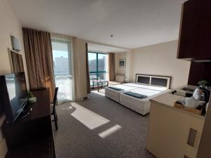 a hotel room with a bed and a television at Berlin Golden Beach Studio in Varna City