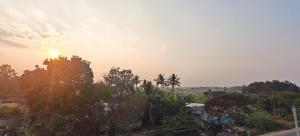 a sunset over a city with trees in the foreground at Sukra Residency in Valavanūr
