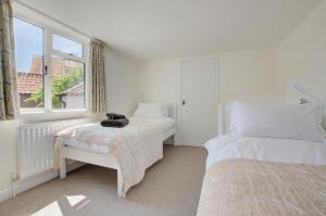a white bedroom with two beds and a window at 5 Bed in Southwold oc-hjames in Southwold