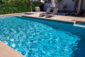 a blue swimming pool with two chairs and an umbrella at NO 5 Hotel in Lekki