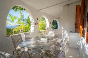 a dining room with a table and chairs and two windows at CAPOVILLAS - Villa Laura with private pool in Vibo Valentia