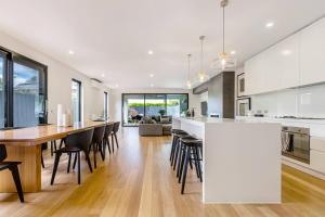 an open kitchen and dining room with a large white island at The Pool Pavilion - Where City meets Beach in Melbourne