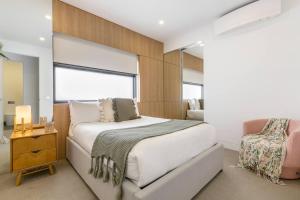 a bedroom with a large white bed and a chair at The Pool Pavilion - Where City meets Beach in Melbourne +44 photos