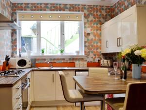 a kitchen with white cabinets and a wooden table at Park View Cottage in Stranraer