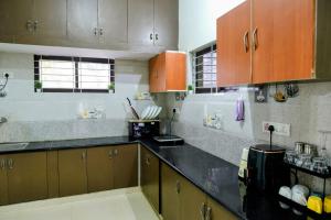 a kitchen with brown cabinets and a black counter top at Aura attic residency in Bangalore