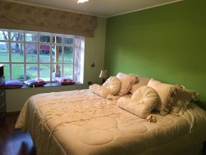 a green bedroom with a large bed with pillows at Casa de Campo, tranquilidad natural in Curicó +27 photos