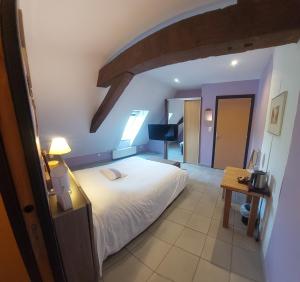 a bedroom with a large white bed and a table at La Forge De Labbaye in Liessies