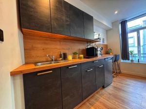 a kitchen with black cabinets and a sink at Le Cocon de Rose & Achille in Boulogne-sur-Mer
