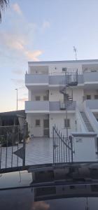 a white building with a balcony and a swimming pool at Ocra Fronte Mare in Torre Mozza