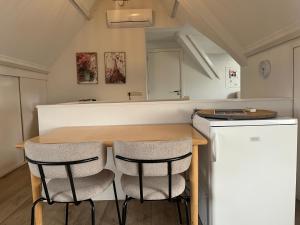 a kitchen with a wooden table and two chairs at B&B De Holevoet in Scherpenzeel