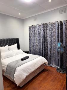 a bedroom with a bed with a black headboard and curtains at HavenTrust Guest house in Goodwood