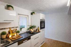 a kitchen with white cabinets and a sink at Schones Apartment mit Charme und privatem Garten in Schwieberdingen +7 photos