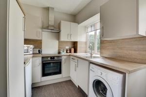 a kitchen with white cabinets and a washer and dryer at 2 Bed in Blakeney oc-1805 in Blakeney