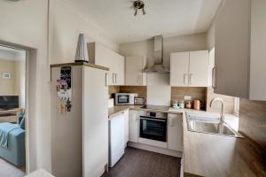 a kitchen with white cabinets and a sink and a refrigerator at 2 Bed in Blakeney oc-1805 in Blakeney