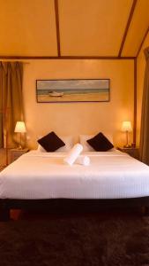 a bedroom with a large white bed with two pillows at Coco Seaweed Resort in Semporna