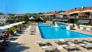 a large swimming pool with lounge chairs and umbrellas at a hotel at Hotel Marina Uno in Lignano Sabbiadoro