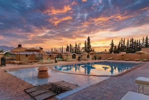 a large swimming pool with a sunset in the background at Riad Elaissi in Taroudant