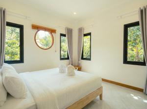 a white bedroom with two stuffed animals on a bed at Garden Villa in Srithanu