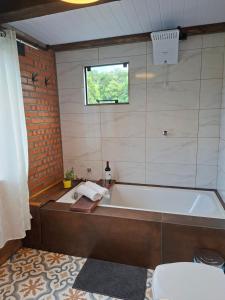 a bathroom with a bath tub and a window at Chalé lindo e confortável! in Massaranduba +22 photos