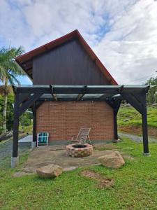 a building with a fire pit in the grass at Chalé lindo e confortável! in Massaranduba