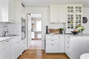 a white kitchen with white cabinets and wooden floors at Luxury villa with pool in Bro