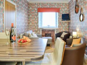 a dining room with a table and a living room at Park View Cottage in Stranraer