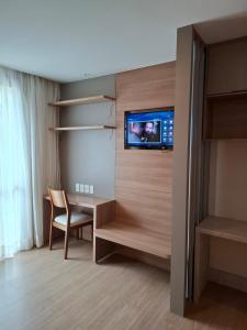 a room with a desk and a tv on a wall at Vista Azul Apart Hotel - Vista Pedra Azul in Pedra Azul