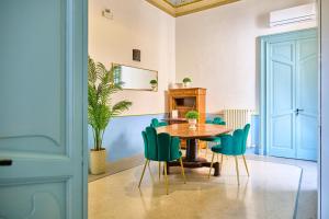 a dining room with a table and green chairs at Palazzo Mercanzia in Lecce
