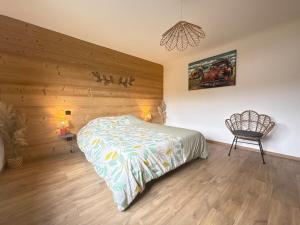 a bedroom with a bed and a chair in it at Le Gite des Fleurs in Ramonchamp