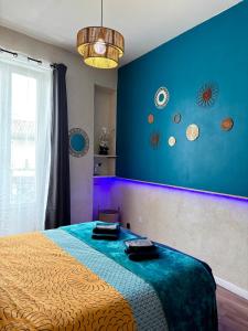 a bedroom with a bed with a blue wall at CLIM - Hypercentre - Arche en pierre in Nîmes +13 photos