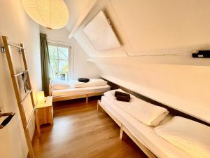 a attic room with two beds and a window at Casa Divera in Noordwijkerhout