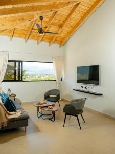a living room with a couch and chairs and a flat screen tv at Ocean Winds Hotel in San Felipe de Puerto Plata