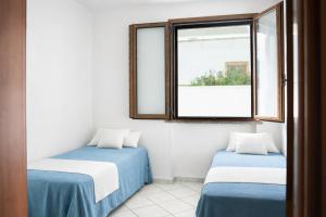 two beds in a room with a window at Casa Saracino 3 - Semplicità Mediterranea in Marina di Pescoluse