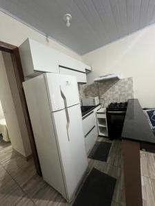 a kitchen with a white refrigerator and a stove at Pertinho do Aeroporto Hospedagem Particular in Várzea Grande