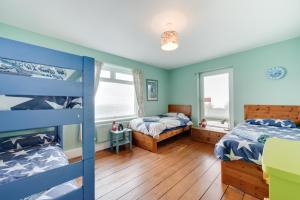 two beds in a room with blue walls and wooden floors at 5 Bed in Woolacombe oc-alba12 in Woolacombe