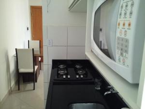 a microwave oven above a stove in a kitchen at Apartamento mobiliado in Feira de Santana