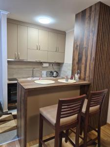 a kitchen with a counter with two chairs and a sink at Apartman Mikulic 2 in Subotica