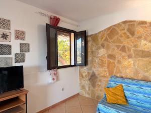 a living room with a tv and a stone wall at Villa Flora Gallipoli in Il Monte