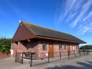 a brick building with a black roof and a fence at Ronam Glamping 2 Berth Pod in Anderby
