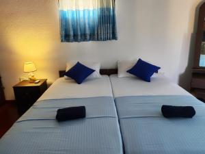 two twin beds in a room with blue pillows at E-Beach Resort in Negombo