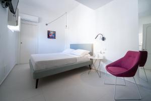 a bedroom with a bed and a pink chair at Ortigia Casa Fab in Syracuse