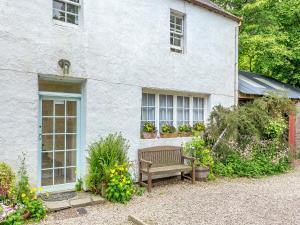 a white house with a bench in front of it at The Cottage in Slickly