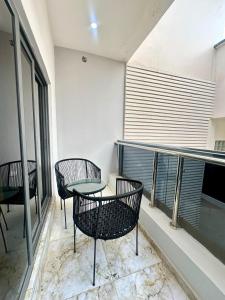 a balcony with three chairs and a table on it at One bedroom apartment Presidential suite in Abuja
