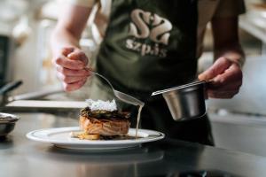 a person preparing a plate of food on a counter at Hotel LIDO in Jurata