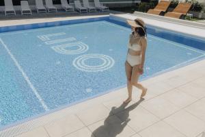 a woman in a bikini standing next to a swimming pool at Hotel LIDO in Jurata