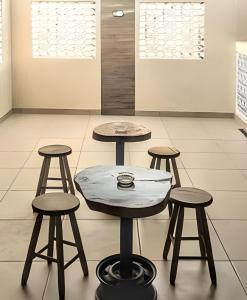 two tables and four stools in a room at Central Praias Suíte 202 com ar, tv, frigobar, banheiro privativo, espaçosa em frente à praça in Cabo Frio